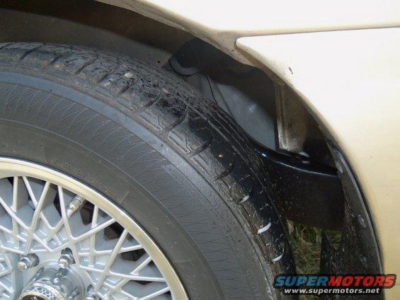 Close-up of a car's wheel well and tire with a wire-spoke rim