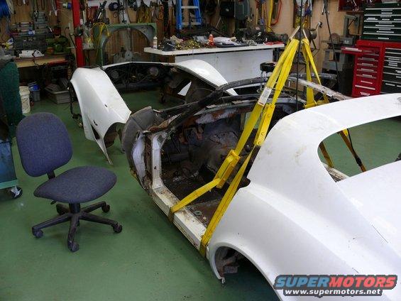 car body on a lift in a workshop, with parts removed