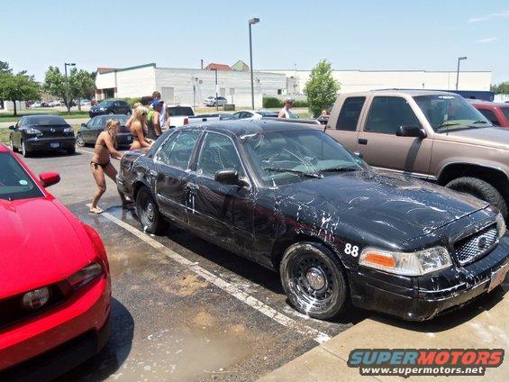 Black sedan with number 88 on the fender, covered in soap, parked at a carwash