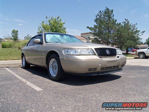 Gold 2000 Mercury Grand Marquis parked in a lot, front 3/4 view
