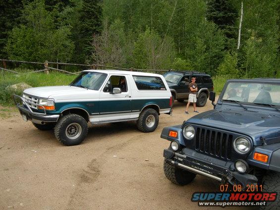 1996 Ford Bronco with green and white paint, parked next to two Jeeps
