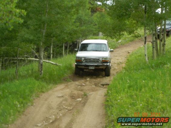 White SUV on a dirt road, front view. Grille suggests 1992 model year