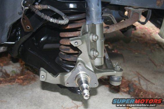 close-up of a car's front suspension assembly with a shock absorber and coil spring