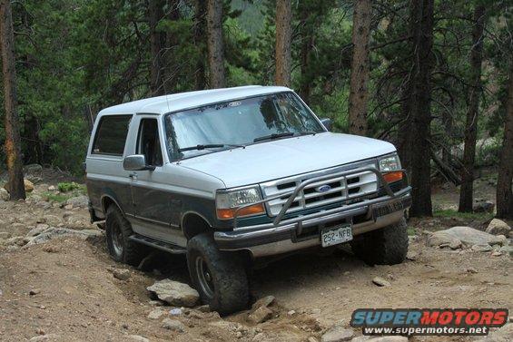 1996 Ford Bronco navigating a rocky, wooded trail. License plate reads 252-NFB