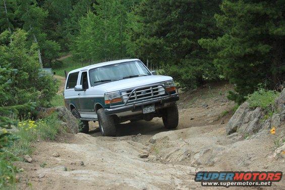 1996 Ford Bronco 3q-front view, white and green exterior, driving on rocky terrain