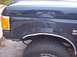 1990 Ford Bronco - The side view shows the fender, wheel, and tire of a dark blue Ford Bronco.