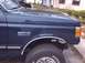 1990 Ford Bronco - A close-up view of the front fender and wheel of a dark blue 1990 Ford Bronco.