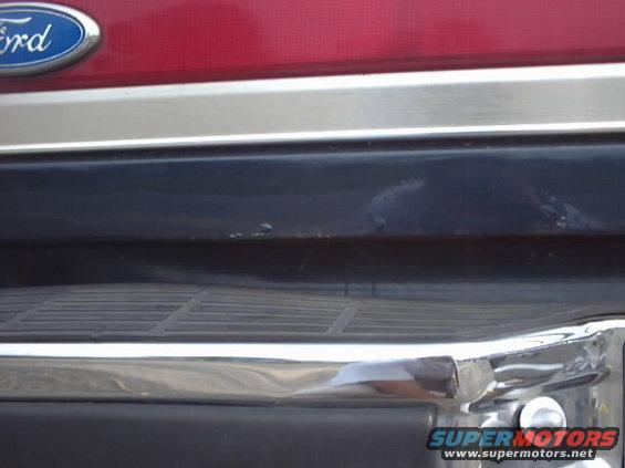 Red Ford Bronco rear with chrome bumper and dark blue lower trim. Visible Ford emblem