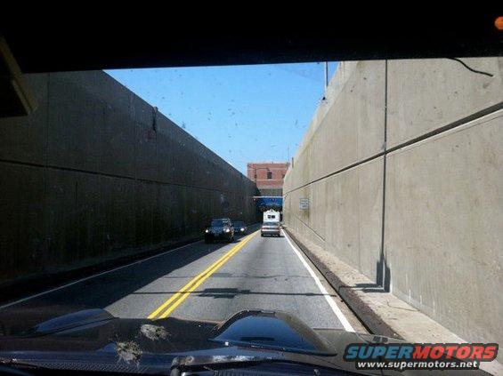 Two cars and an RV on a road between concrete walls