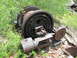 1994 Ford Bronco - An old, large industrial winch mechanism sits abandoned and overgrown in a wooded area.