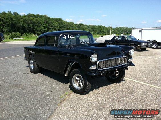 Black 1955 Chevrolet Bel Air drag car with hood scoop and racing slicks parked on asphalt