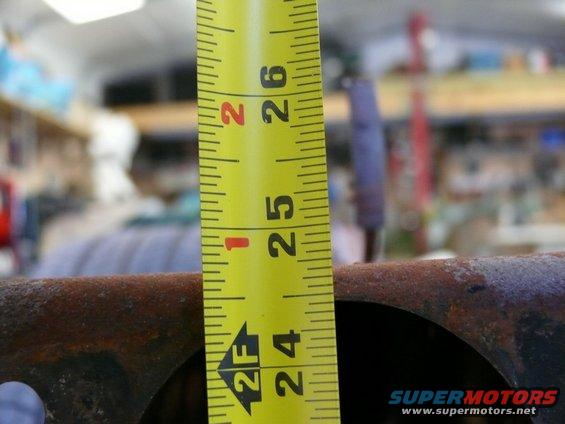 Tape measure showing 24 to 26 inches against rusty metal