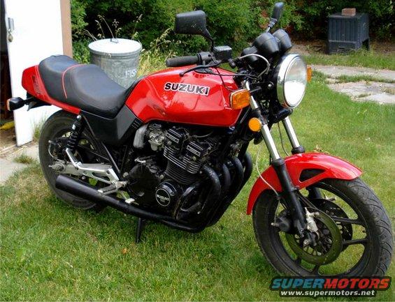 red Suzuki motorcycle parked on grass, side view