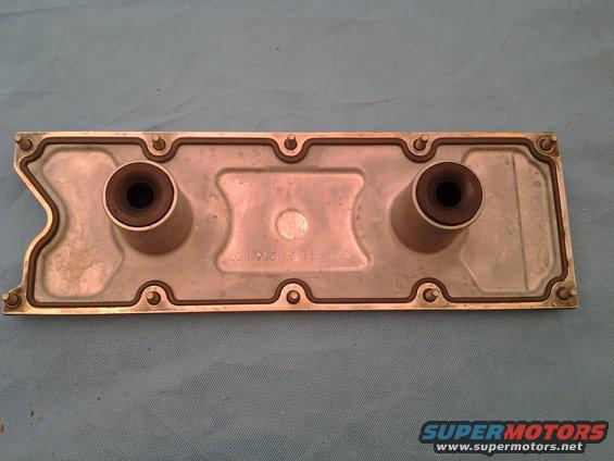 Silver engine part with two rubber grommets and visible text