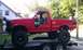 1994 Ford F-250 - This lifted 1994 Ford F-250 pickup truck features oversized tires and a bright red exterior.