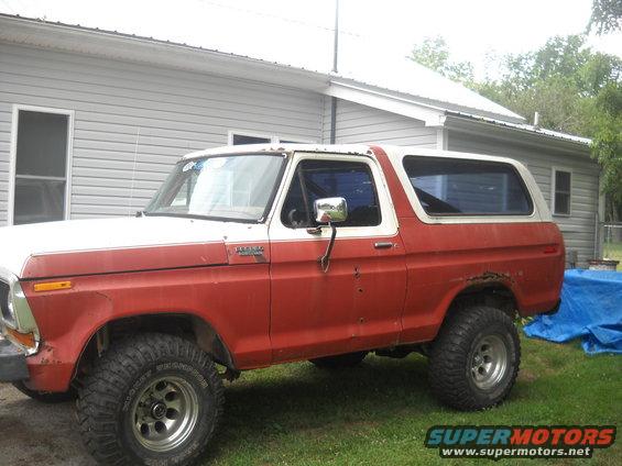 Red and white Ford Bronco, side view, showing rust on rear quarter panel and dented fender