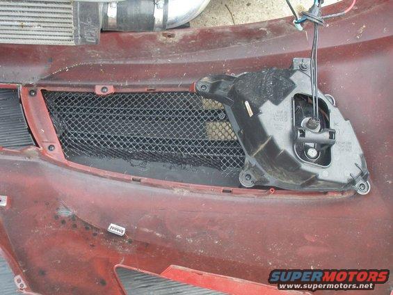 Car bumper with mesh grille and fog light housing removed. Intercooler piping visible above