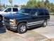 1995 Chevrolet Tahoe - A dark green SUV is parked on a concrete surface next to a silver pickup truck.
