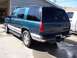 1995 Chevrolet Tahoe - A teal 1995 Chevrolet Tahoe SUV is viewed from the rear, parked next to a white truck.