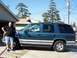 1995 Chevrolet Tahoe - A man stands beside a teal and silver 1995 Chevrolet Tahoe SUV parked in front of a garage.