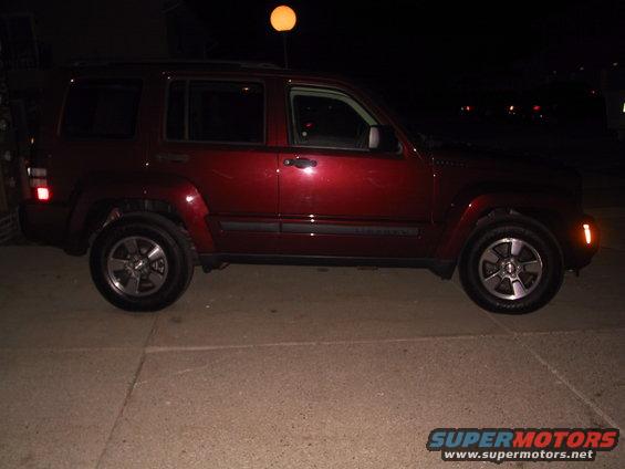 Side view of a red 2008 Jeep Liberty parked on concrete at night