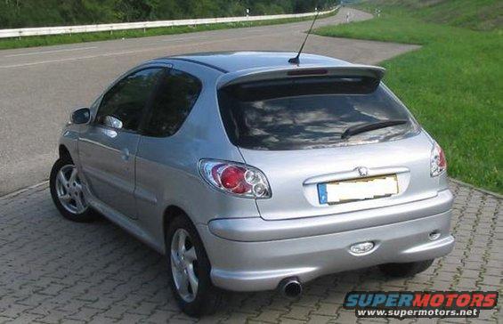 Silver hatchback car parked on a paved surface next to a road, rear view