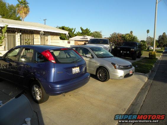 Silver Ford Focus parked in driveway next to a blue Ford Focus and two trucks