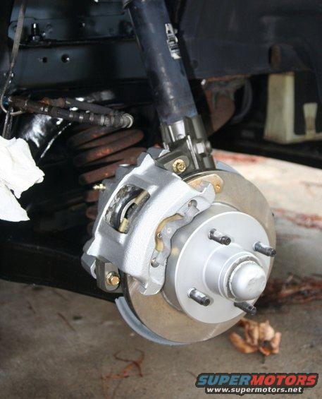 Front brake assembly with caliper, rotor, and coil spring