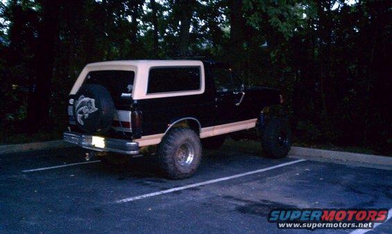 Rear view of a lifted black and tan Ford Bronco with a spare tire mounted on the tailgate
