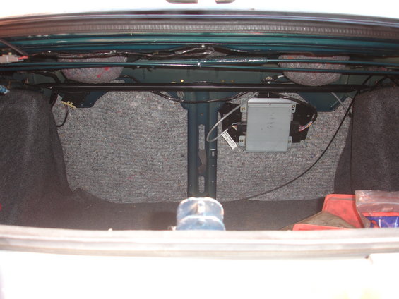 Trunk interior with grey carpet lining, visible wiring, and a silver electronic module mounted on the side