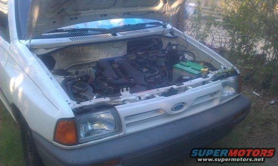 White hatchback with hood open showing engine bay. Ford logo visible on grille