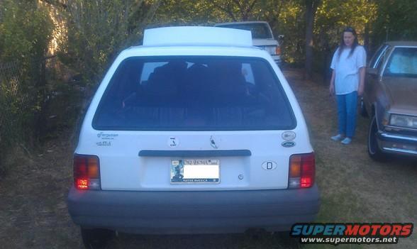 1991 Ford Festiva rear view with a person standing next to it and another car behind