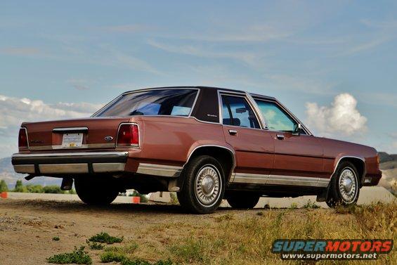 Rear view of a brown Ford Crown Victoria parked on a dirt road