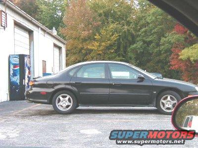 Black sedan parked next to a Pepsi vending machine outside a garage