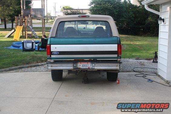 Rear view of a green and white 1996 Ford Bronco with a tan top