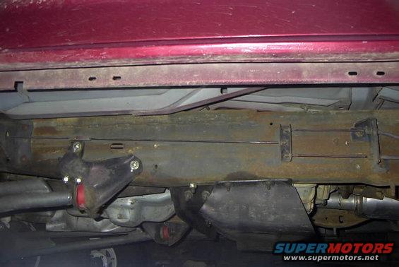 Underbody view of red vehicle showing suspension components and frame