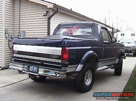 Dark blue Ford Bronco parked in driveway, rear view. Another SUV is parked behind it