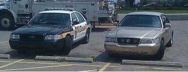 Gold sedan and a police car parked in a lot