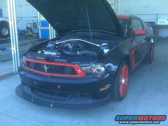 Black and red Ford Mustang, hood open, red wheels, front view