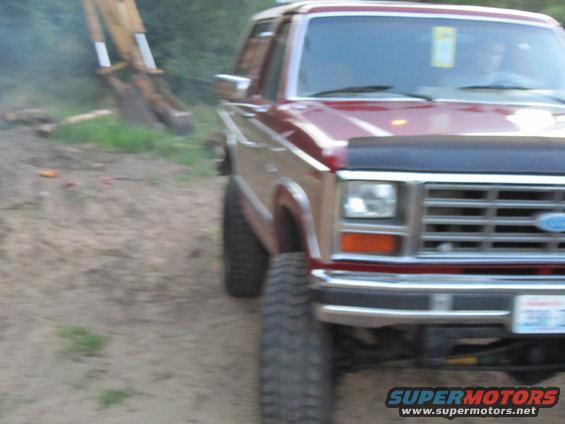 Red Ford Bronco front 3/4 view with black bug deflector and aftermarket wheels