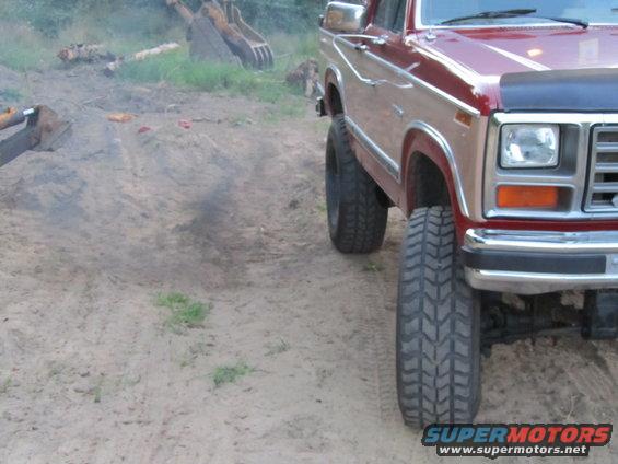 Red and tan Ford F-Series truck with large tires, seen from the front quarter