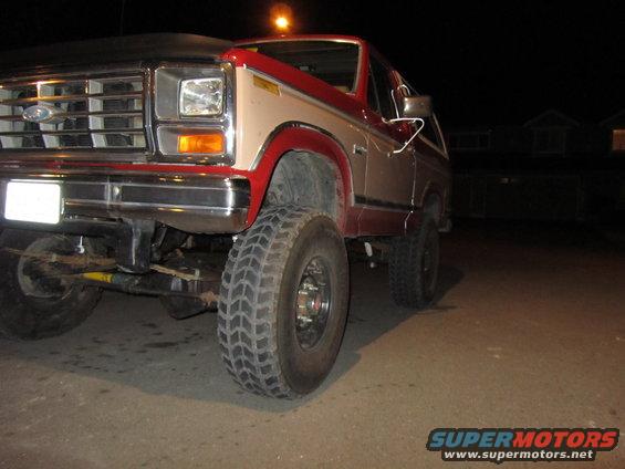Front corner of a two-tone red and tan Ford Bronco with aftermarket wheels and tires