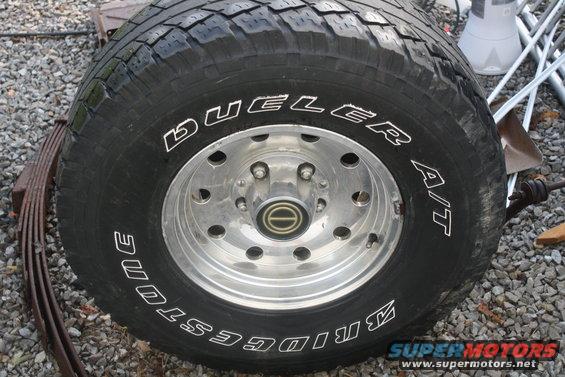 Bridgestone Dueler A/T tire on a chrome wheel with a leaf spring nearby