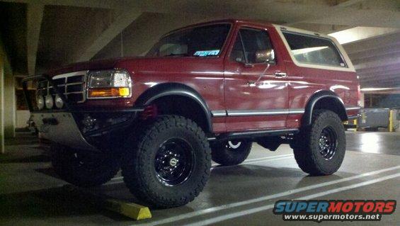 Red 1989 Ford Bronco 3/4 front view, lifted with off-road tires and aftermarket bumper