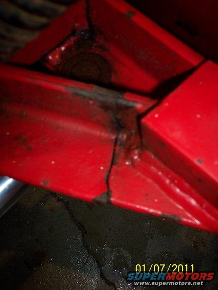 Red metal frame with a crack and rust, close-up view