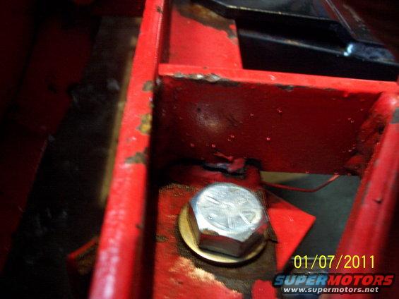 Close-up of a bolt on a red metal frame with visible rust