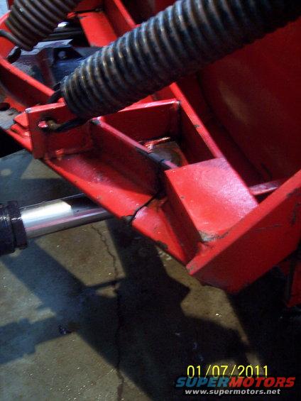 close-up of red plow mechanism with hydraulic cylinder and bellows