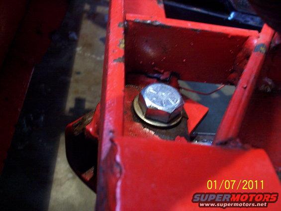 Close-up of a large bolt on red painted metal with a date stamp