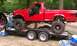1994 Ford F-250 - A red 1994 Ford F-250 pickup truck, heavily modified with a lift kit and large tires, is loaded onto a trailer.