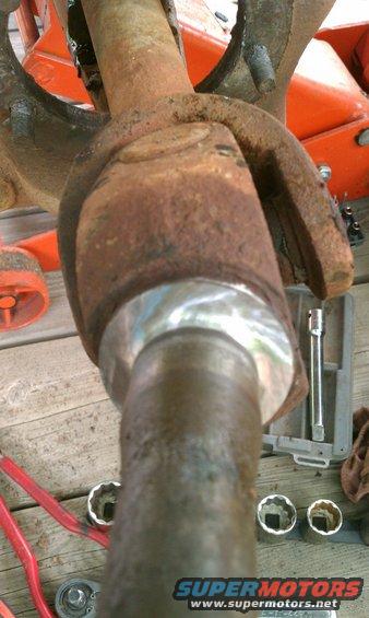 close-up of rusty driveshaft u-joint with tools nearby
